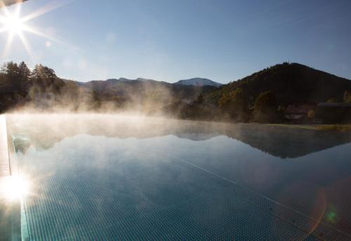 a misty lake with the sun in the background at Haubers Naturresort in Oberstaufen