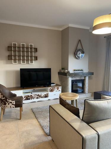 a living room with a couch and a tv and a fireplace at Estrela da Montanha in Penhas da Saúde