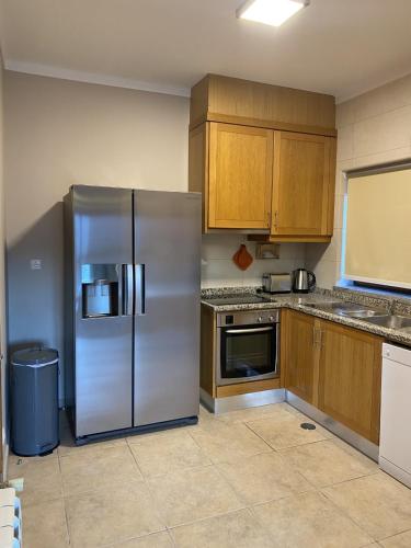 a kitchen with a stainless steel refrigerator and wooden cabinets at Estrela da Montanha in Penhas da Saúde