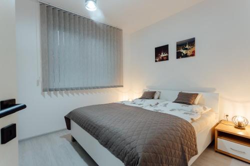 a white bedroom with a bed and a window at Apartmán vo vile Kammergraf in Banská Štiavnica