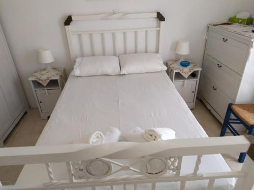 - un lit blanc dans une chambre avec deux tables dans l'établissement Traditional House Marivilla, à Mastichari