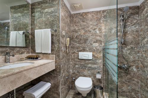 a bathroom with a shower and a toilet and a sink at Oz Hotels Incekum Beach in Alanya