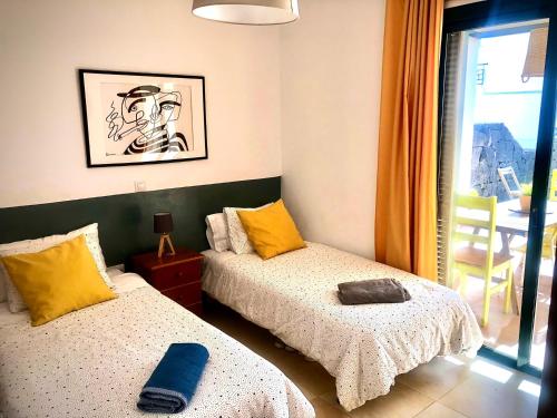 ein Zimmer mit zwei Betten und einem Fenster in der Unterkunft Alegranza, apartamento de 3 habitaciones en Lanzarote in Costa Teguise