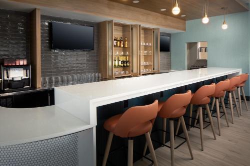 a bar with orange bar stools and a tv at Holiday Inn Cheshire - Southington by IHG in Southington