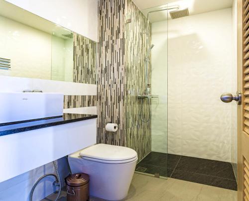 カロンビーチにあるOneLoft Hotelのトイレとガラスのシャワー付きのバスルーム