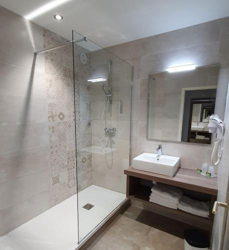 une salle de bain avec une douche en verre et un lavabo dans l'établissement Logis Hotel Restaurant de l'Abbaye, à Ferrières