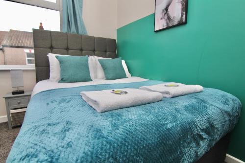 a blue bedroom with a bed with towels on it at Mount Haven's Rest - Free Parking, Netflix & Private Back Garden in Coventry