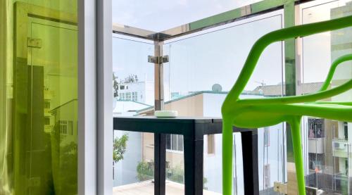 a table and a green chair in front of a window at Marine Holiday in Hulhumale