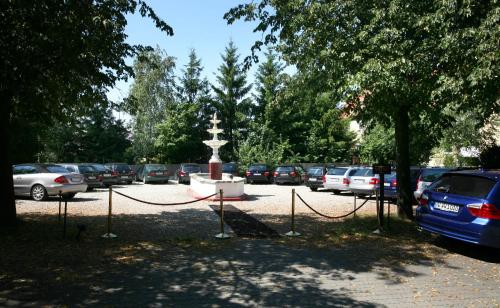 a parking lot with a fountain and parked cars at Runas Air Muc Park Sleep & Fly in Hallbergmoos