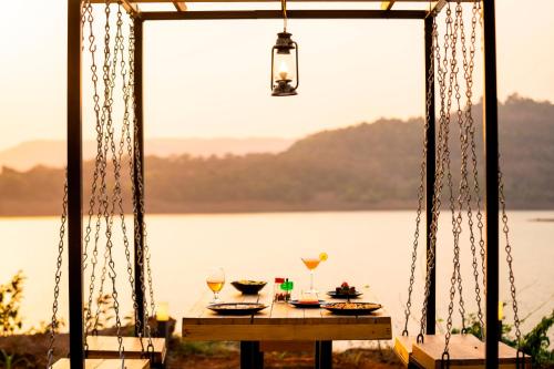 a table with food and wine glasses on a swing at Zostel Plus Lonavala in Lonavala