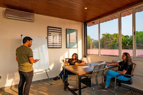 a group of people sitting around a table in a room at Zostel Plus Lonavala in Lonavala