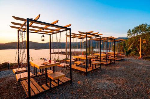a row of tables and benches in front of a lake at Zostel Plus Lonavala in Lonavala