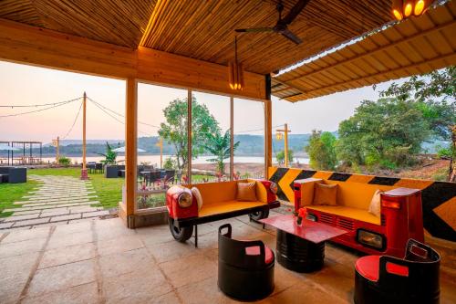 a screened in porch with two couches and a table at Zostel Plus Lonavala in Lonavala