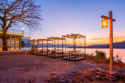 a row of tables in front of a building next to the water at Zostel Plus Lonavala in Lonavala