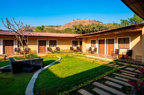 a building with a yard with chairs and tables at Zostel Plus Lonavala in Lonavala