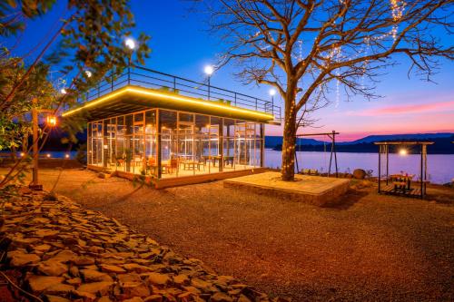a building with a tree in front of a body of water at Zostel Plus Lonavala in Lonavala