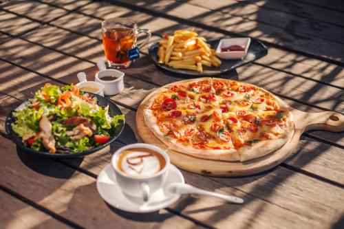 a table with a pizza and a salad and a cup of coffee at The Bivou Lijiang in Lijiang