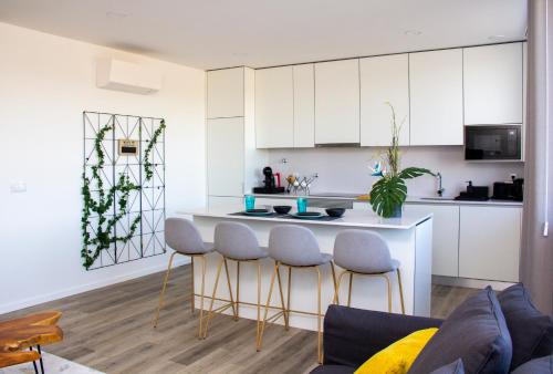 a kitchen with white cabinets and a kitchen island with stools at Casa das Falcoeiras - AL com vista Ria in Aveiro