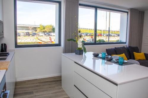 a kitchen with a white counter and two windows at Casa das Falcoeiras - AL com vista Ria in Aveiro