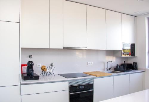a white kitchen with white cabinets and appliances at Casa das Falcoeiras - AL com vista Ria in Aveiro
