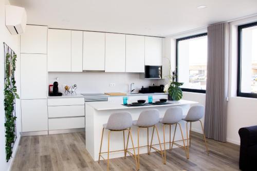 a kitchen with white cabinets and a white island with stools at Casa das Falcoeiras - AL com vista Ria in Aveiro