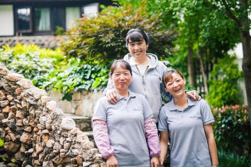 a woman and two children standing next to a stone wall at The Bivou Lijiang in Lijiang