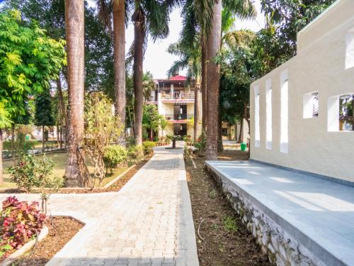 a walkway in front of a building with palm trees at Royal Tiger Luxury Resort in Sauraha