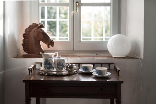 a table with cups and a horse statue next to a window at Stone House 15th Century in Vicchio