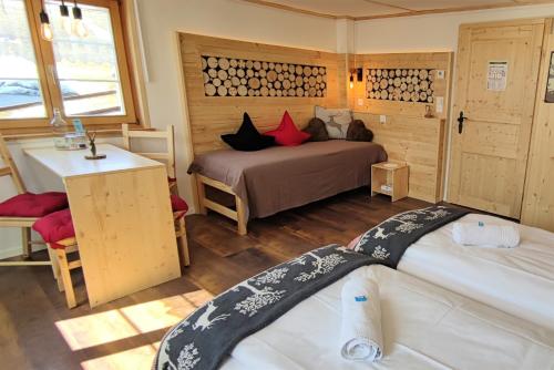 a bedroom with two beds and a table and a desk at Gasthaus Alpina in Tschappina
