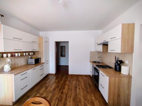 a kitchen with white cabinets and a wooden floor at Apartament nad Strumykiem in Tylicz