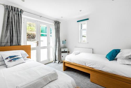 een slaapkamer met twee bedden en een raam bij Eveley Cottage in Boscastle