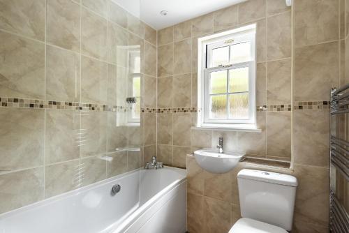 uma casa de banho com uma banheira, um WC e um lavatório. em Eveley Cottage em Boscastle