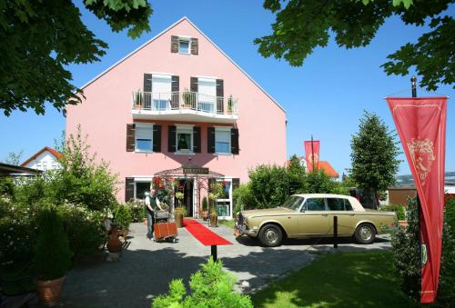 une vieille voiture garée devant une maison rose dans l'établissement Runa´s Hotel, à Hallbergmoos