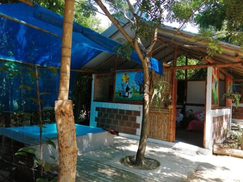 a house with a blue roof and a tree at Finca Ecoturistica LOS JAGUEYES in Baraya