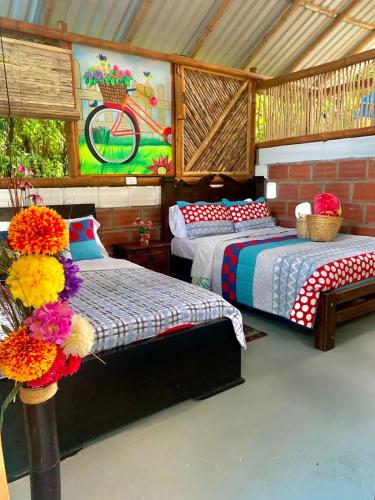 a bedroom with two beds and a painting on the wall at Finca Ecoturistica LOS JAGUEYES in Baraya