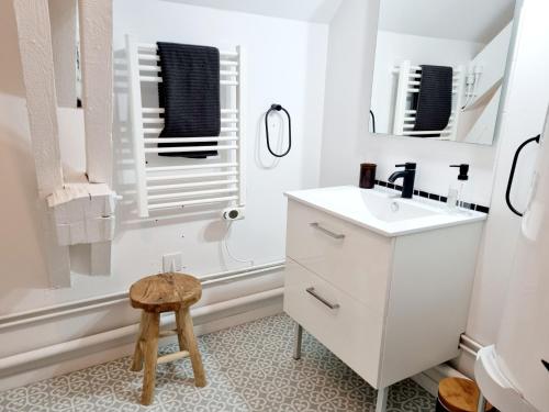 - une salle de bains blanche pourvue d'un lavabo et d'un tabouret dans l'établissement Meublés du chêne vert, cœur de Jarnac, à Jarnac