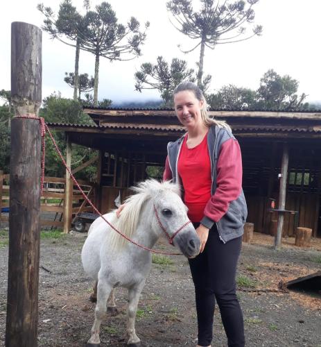 a woman is standing next to a white pony at Pousada Vale da Imbuia chalé para temporada in Urubici