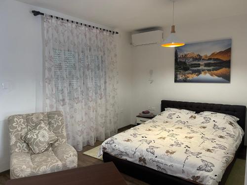 a bedroom with a bed and a chair at Montana Apartmani in Konjic