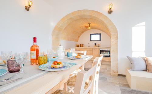 a kitchen and dining room with a table with plates of food at Villa Li Tratturi Luxury by HDSalento in Corsano