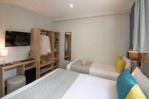 a hotel room with two beds and a tv at Bristol Nice in Nice