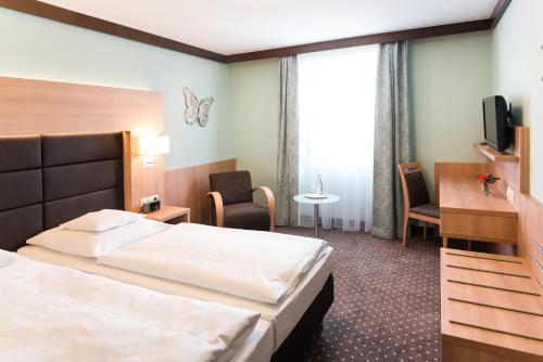 a hotel room with a bed and a tv at Hotel Gumberger GmbH Garni in Neufahrn bei Freising