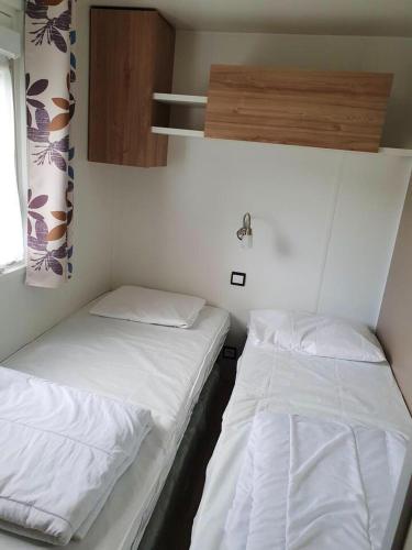 deux lits dans une petite pièce avec des draps blancs dans l'établissement Bungalow cosy en campagne à Onzain avec piscine partagée, à Onzain