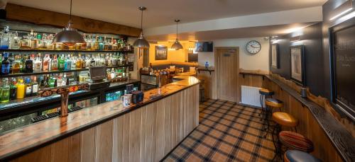 a bar in a pub with a counter and shelves at Black Bull in Lauder