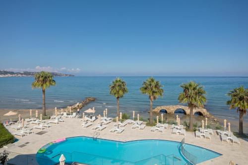 - une piscine sur la plage avec des chaises et des palmiers dans l'établissement Xenos Kamara Beach, à Argassi