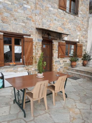 a wooden table and chairs on a stone patio at Kirmilis Mansion in Makrinítsa