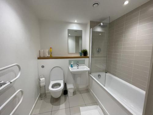a bathroom with a toilet and a tub and a sink at Stratford Luxury Apartments in London