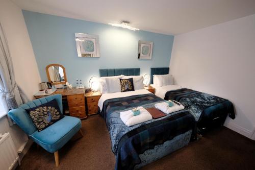 a bedroom with two beds and a blue chair at Toulson Court in Scarborough