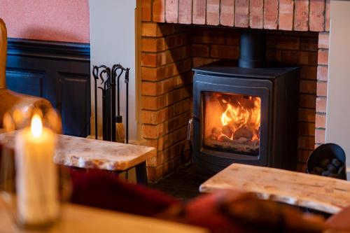 a fireplace with a stove with a fire in it at Black Bull in Lauder