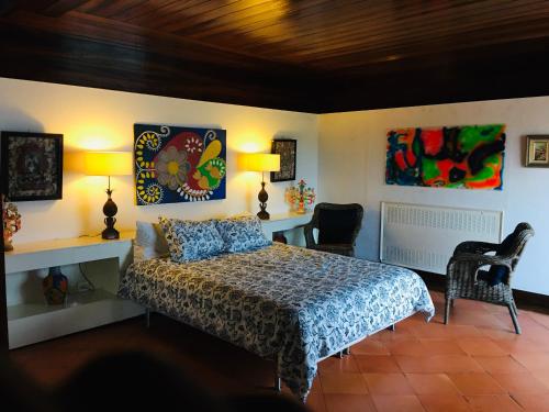 a bedroom with a bed with two chairs and two lamps at Herdade AMÁLIA RODRIGUES in Zambujeira do Mar