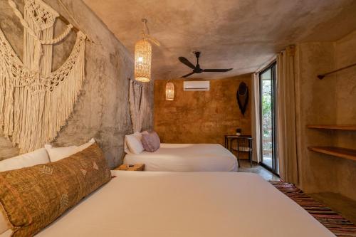 1 dormitorio con 2 camas y ventana en Casa Coyote Tulum en Tulum